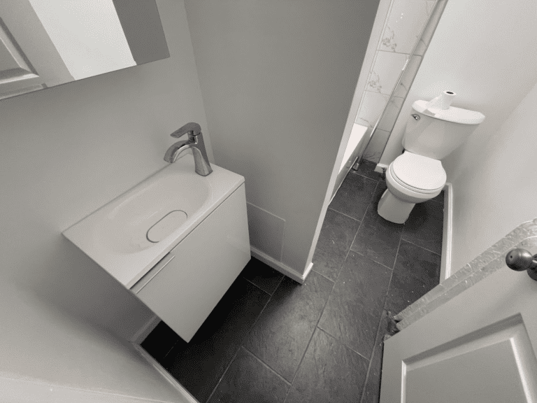 Bathroom after renovation with floating vanity and dark floor tile